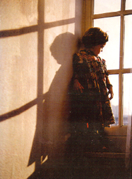 Kind an einer Fensterscheibe gelent schaut nach draußen 